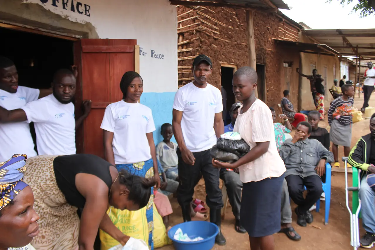 VPEACE volunteers in white T-shirts handing out food supplies to families in a refugee community